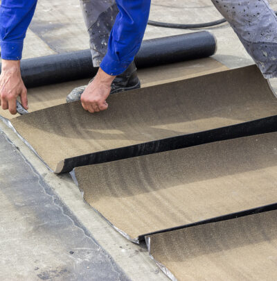roofing worker cutting insulation bitumen material rolls