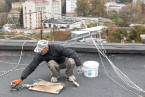 worker performing roof repairs at a school